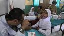Dokter memeriksa seorang anak saat mengikuti Bulan Imunisasi Anak sekolah (BIAS) di SDN 11 Pagi, Lubang Buaya, Jakarta, Selasa (4/10). Kegiatan ini untuk mewujudkan Indonesia bebas dari kanker serviks. (Liputan6.com/Faizal Fanani)