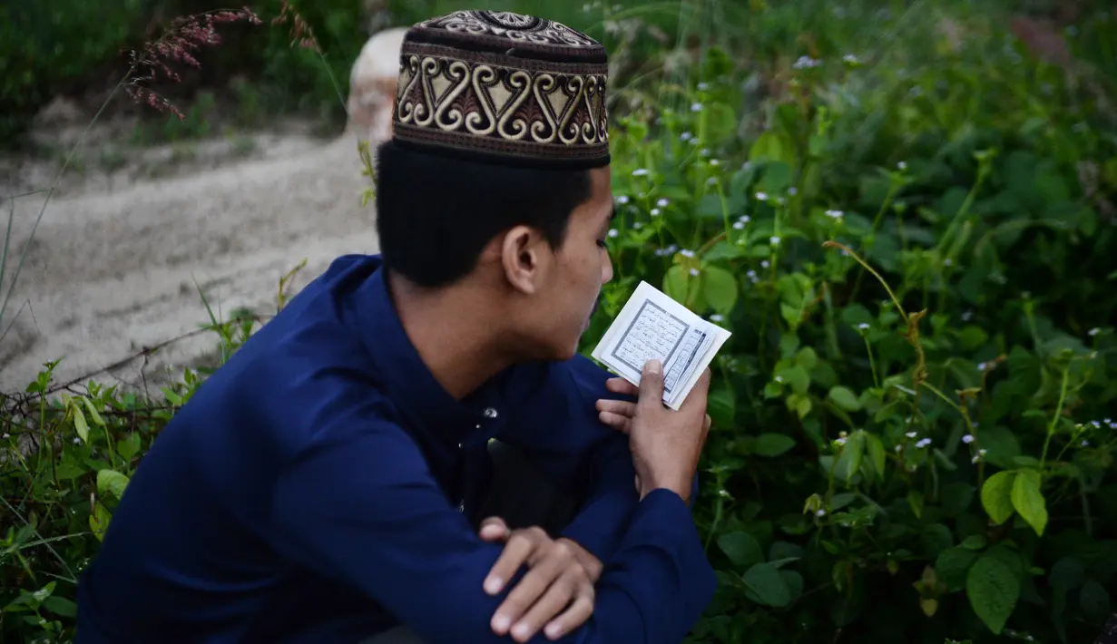 Seorang pria memanjatkan doa di makam kerabatnya saat Idul Fitri di Provinsi Narathiwat, Thailand, Rabu (5/6/2019). Tradisi ziarah kubur saat Idul Fitri ini mirip dengan apa yang biasa dilakukan muslim di Indonesia. (MADAREE TOHLALA/AFP)