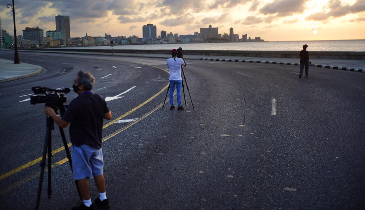 Wartawan mengenakan masker saat merekam gambar dari Malecon yang kosong selama jam malam di Havana, Kuba, Selasa (1/9/2020). Otoritas Kuba menerapkan lockdown selama 15 hari di Havana untuk keluar dari penularan COVID-19 tingkat rendah tetapi terus-menerus. (AP Photo/Ramon Espinosa)