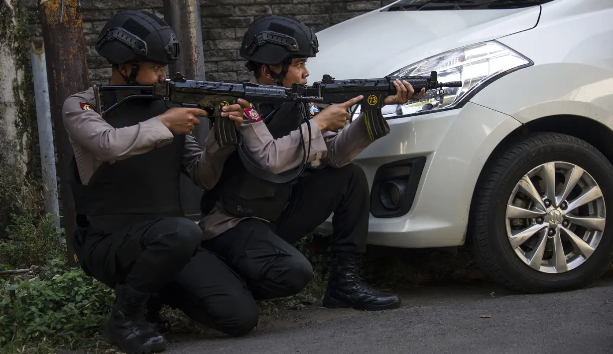 Aparat kepolisian mengambil posisi saat melakukan penjagaan menyusul serangan bom bunuh diri di Polrestabes Surabaya, Senin (14/5). Seluruh akses menuju Mapolrestabes ditutup total dan tiap jalur dijaga polisi bersenjata laras panjang (AFP/JUNI KRISWANTO)