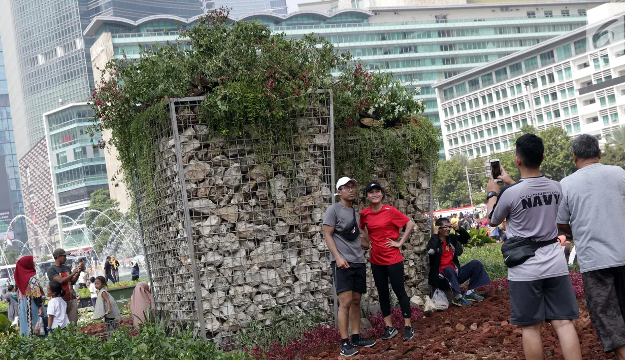 Warga berfoto di area taman dekat Instalasi Gabion saat CFD di kawasan Bundaran Hotel Indonesia, Jakarta, Minggu (25/8/2019). Instalasi Gabion berdiri di lokasi bekas seni anyaman bambu Getah Getih dan diletakkan bebatuan sebagai penghias. (Liputan6.com/Helmi Fithriansyah)