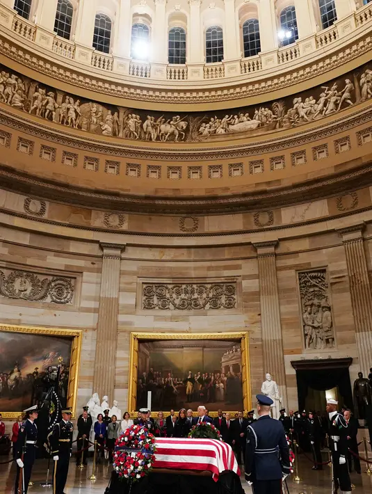 Presiden AS Donald Trump dan Melania Trump memberikan penghormatan terakhir kepada George HW Bush di Gedung Capitol, Washington, Senin (3/12). Jenazah Presiden ke-41 AS itu disemayamkan di Rotunda Capitol Hill selama beberapa hari. (MANDEL NGAN/ AFP)