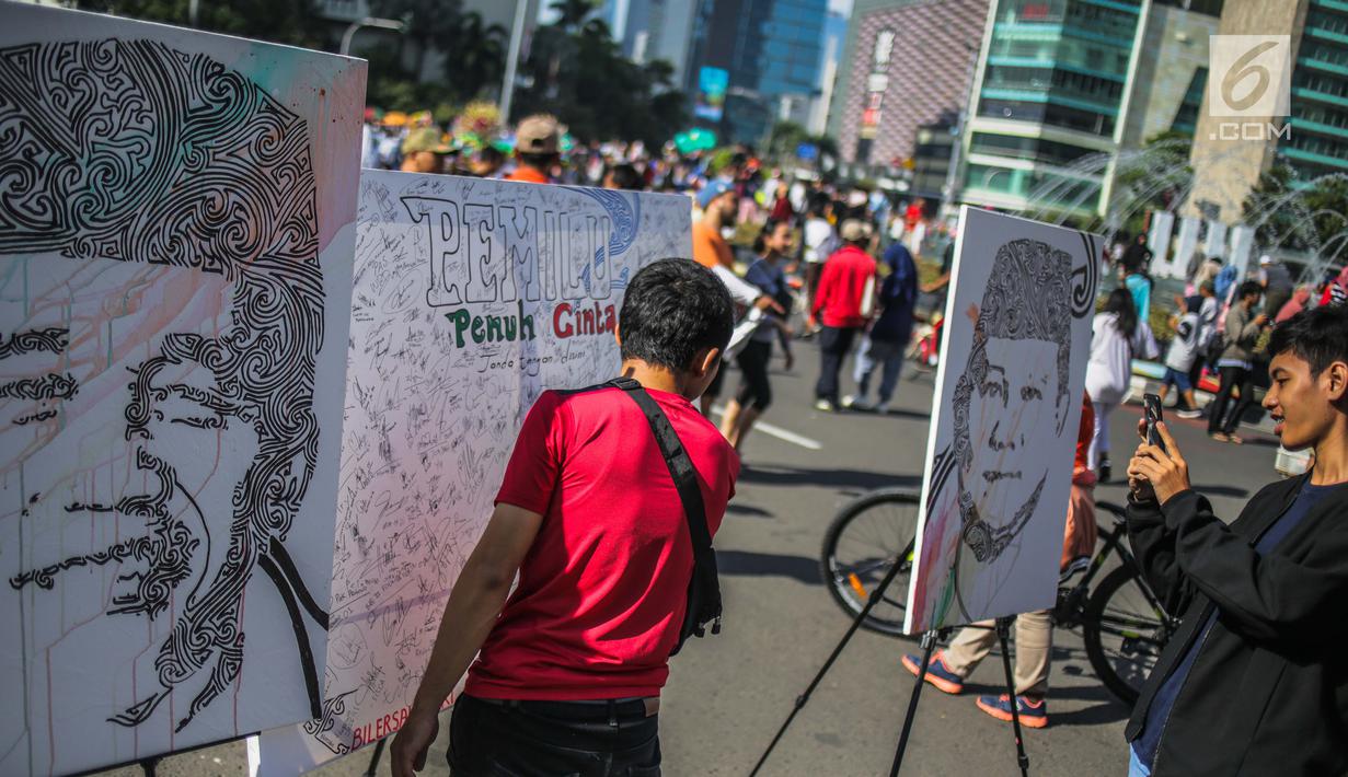 Masyarakat menandatangani dilukisan capres 01 dan 02  yang bertema ‘ Pemilu Penuh Cinta’  saat Car Free day di kawasan Bundaran HI, Jakarta, MInggu (14/4). Kampanye tersebut untuk mengajak masyarakat untuk berpartisipasi dalam Pemilu secara Damai. (Liputan6.com/Faizal Fanani)