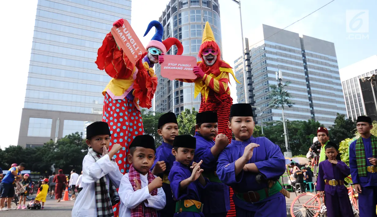 Pesilat cilik bersama badut berpose saat social community gathering Satgas Saber Pungli di Jakarta, Minggu (17/9). Kemenko Polhukam meluncurkan maskot dan melakukan sosialisasi satgas saber pungli. (Liputan6.com/Helmi Fithriansyah) 