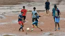 Anak-anak sekolah India bermain bola dekat genangan air di Bangalore, India, Rabu (11/11/2015) WIB.  (AFP Photo/Manjunath Kiran)