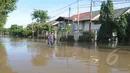 Hujan yang mengguyur Jakarta sejak Minggu (8/2) lalu, membuat Waduk Ria Rio meluap. Seorang warga tampak melintasi jalan yang tergenang banjir di kawasan Perumahan Pulomas, Jakarta, Selasa (10/2/2015). (Liputan6.com/Herman Zakharia)