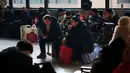 Gelombang mudik tahunan terbesar di dunia ini resmi dimulai sejak Senin (2/2/2026) atau tepat 15 hari menjelang perayaan Tahun Baru Imlek atau Festival Musim Semi 2026. Tampak dalam foto, para penumpang duduk di samping barang bawaan mereka sambil menunggu di stasiun kereta api dalam perjalanan pulang selama liburan Tahun Baru Imlek di Beijing, China, Selasa 10 Februari 2026. (AP Photo/Vincent Thian)