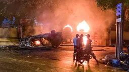 Sebuah kendaraan milik personel keamanan dan bus yang dibakar terlihat di dekat kediaman resmi Perdana Menteri Mahinda Rajapaksa yang akan keluar dari Sri Lanka di Kolombo 9 Mei 2022. Sedikitnya tiga orang tewas dan lebih dari 150 terluka pada 9 Mei dalam gelombang kekerasan antara pendukung pemerintah dan demonstran yang menuntut pengunduran diri Presiden Gotabaya Rajapaksa. (ISHARA S. KODIKARA / AFP)