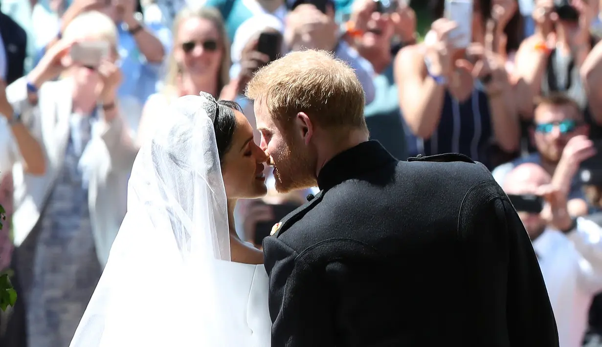 Warga mengambil gambar ciuman Pangeran Harry dan Meghan Markle di tangga Pintu Barat St George's Chapel, Kastil Windsor, Inggris, Sabtu (19/5). Pangeran Harry dan Meghan Markle telah resmi menikah. (Danny Lawson/pool photo via AP)