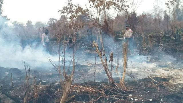 Polisi berada di kebakaran lahan untuk memadamkan titik api.