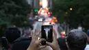 Orang-orang mengambil gambar saat matahari terbenam di Manhattan ketika fenomena "Manhattanhenge" di 42nd street, New York, Senin (11/7/2022). Manhattanhenge adalah keadaan dimana matahari terbenam tepat berada dalam garis lurus dengan jalanan Manhattan yang melintang dari timur ke barat. (Yuki IWAMURA / AFP)