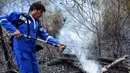 Presiden Bolivia Evo Morales menyemprotkan air saat berusaha memadamkan api dalam kebakaran hutan di pinggiran Robore, Bolivia, Selasa (27/8/2019). Kebakaran hutan membuatnya menunda kampanye pemilihan presiden selama sepekan. (Raul Martinez/Bolivia's Communication Ministry press office via AP)