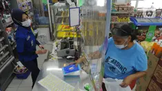 Pekerja melayani pembeli dari balik plastik pembatas pada sebuah minimarket di kawasan Cinere, Depok, Jawa Barat, Rabu (8/4/2020). Penggunaan plastik pembatas tersebut bertujuan untuk mengantisipasi penyebaran virus corona atau COVID-19 sebagai bentuk social distancing. (merdeka.com/Arie Basuki)