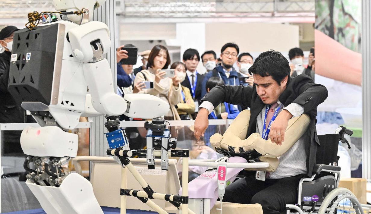Sebuah robot memeragakan membantu memindahkan seorang pria ke kursi roda. (Richard A. Brooks/AFP)