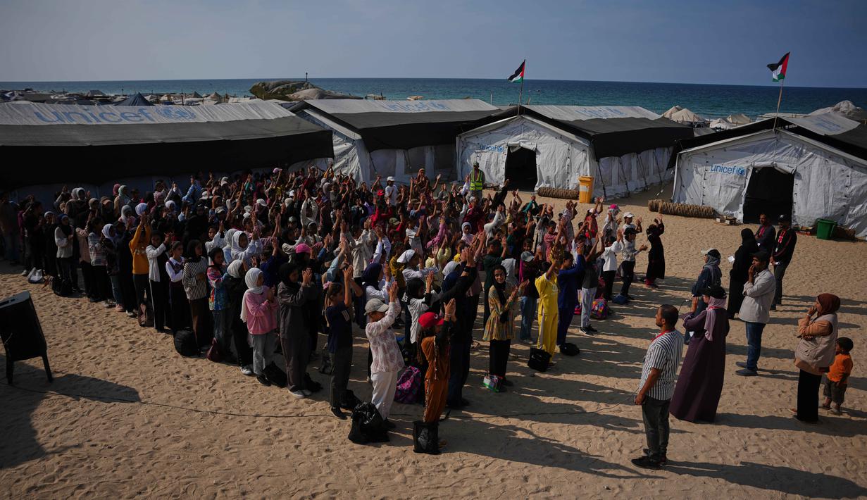 Para siswa menghadiri upacara pagi di sebuah sekolah yang didirikan di pantai di Khan Younis, bagian selatan Jalur Gaza, pada Rabu 12 November 2025. Menyusul kesepatan gencatan senjata yang berlaku antara Isreal dan Hamas sejak 10 Oktober 2025, sebagian pelajar di Gaza telah kembali ke sekolah secara bertahap. (AP Photo/Abdel Kareem Hana)