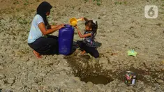 Seorang anak bersama ibunya mengambil air pada galian sumur di tengah aliran Sungai Cihoe, Kamis (28/9/2023). Warga Desa Sukagalih, Jonggol, Bogor, mengalami kesulitan air bersih di tengah fenomena El Nino yang menyebabkan musim kemarau berkepanjangan. (merdeka.com/Arie Basuki)