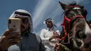 Seorang pria berselfie dengan kuda saudaranya yang memenangkan perlombaan di sebuah festival kuda Arab di Karhuk, Hassakeh, Suriah (5/5/2019). Kuda-kuda tersebut berasal dari seluruh bagian timur laut Suriah bertemu untuk balapan. (AP Photo/Baderkhan Ahmad)