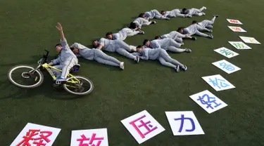 Sejumlah siswa berpose di rumput membuat slogan ""release your stress, let your dream fly" sebelum mengikuti ujian masuk perguruan tinggi di sebuah sekolah di Handan, Provinsi Hebei China utara (24/5). (AFP PHOTO/STR)