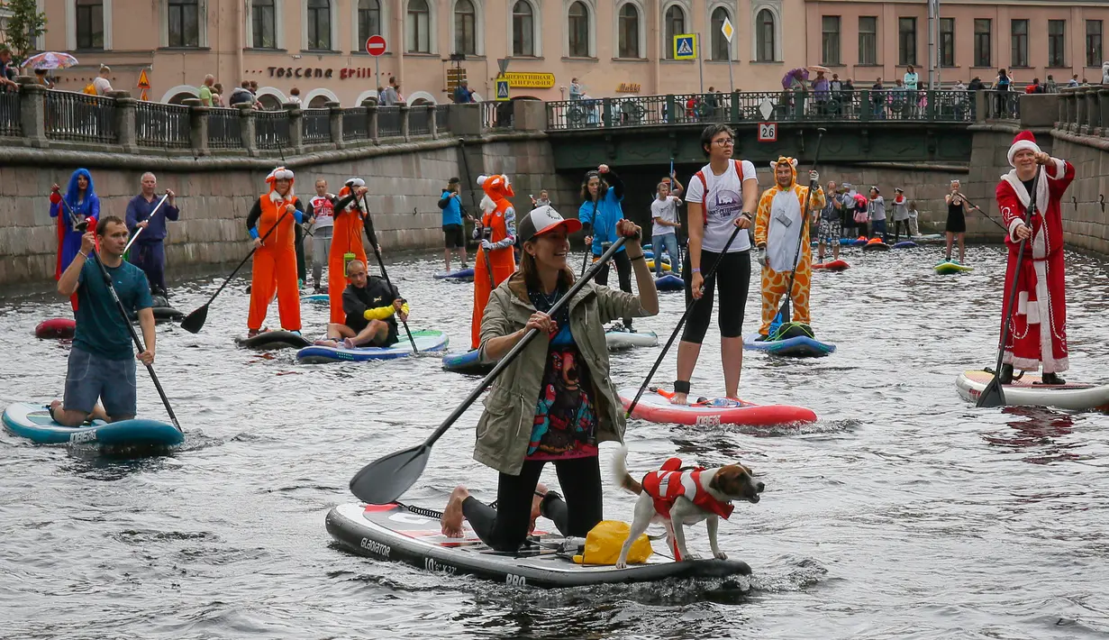 Seorang wanita membawa anjingnya mendayung "paddle board" di kanal Griboedov pada festival SUP (Stand Up Paddle)-Surfing di St.Petersburg, Rusia, Minggu (12/8). Dalam paddling, papan digerakkan dengan cara mendayung sambil berdiri. (AP/Dmitri Lovetsky)