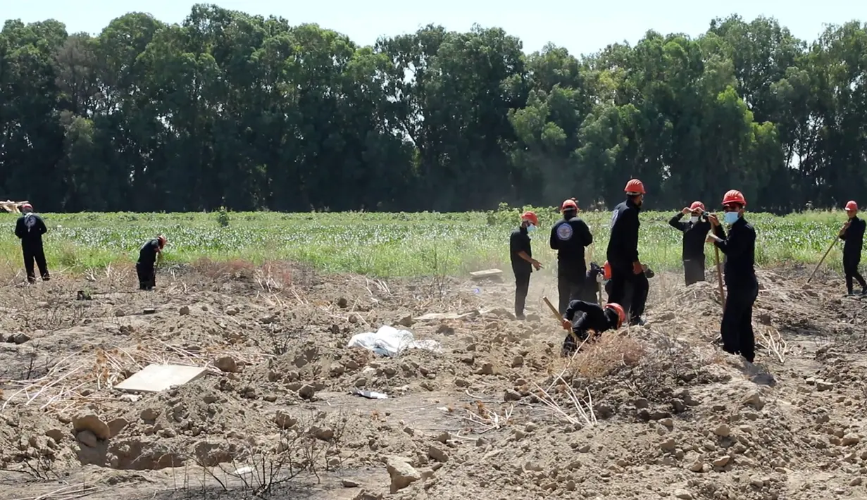 Gambar dari video pada 14 Juli 2019, pekerja Dewan Sipil Raqqa menggali kuburan massal berisi tulang belulang manusia di Raqqa, Suriah, 14 Juli 2019. Sejauh ini para pekerja telah menemukan 313 mayat dari kuburan massal yang ditemukan bulan lalu di dekat kota di Suriah utara tersebut. (AP Photo)