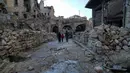 Sebuah keluarga berjalan diantara reruntuhan bangunan pasar lama di kota tua Aleppo, Suriah (21/1). Pada tahun 1986, kota kuno Aleppo dinyatakan sebagai situs warisan dunia UNESCO. (AP Photo / Mstyslav Chernov)