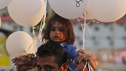 Pria dan anaknya memegang balon saat upacara untuk memperingati peristiwa ledakan pelabuhan 4 Agustus di Beirut, Lebanon, 4 Oktober 2020. Dua ledakan yang mengguncang Pelabuhan Beirut menghancurkan sebagian kota dan menewaskan sekitar 190 orang serta melukai 6.000 lainnya. (Xinhua/Bilal Jawich)