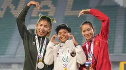 Dina Aulia menjadi yang tercepat dengan 13,21 detik, disusul Emilia Nova (13,27 detik) dan pelari Vietnam, Huynh Thi My Tien, yang membukukan waktu 13,43 detik. Tampak dalam foto, atlet lari gawang putri Indonesia, Emilia Nova (kir) dan Dina Aulia merayakan kemenangan bersama Thi My Tien Huynh (kanan) dari Vietnam saat upacara pemberian medali untuk final lari gawang 100 meter putri di SEA Games ke-33 di Bangkok, Thailand, Jumat 12 Desember 2025. (AP Photo/Achmad Ibrahim)