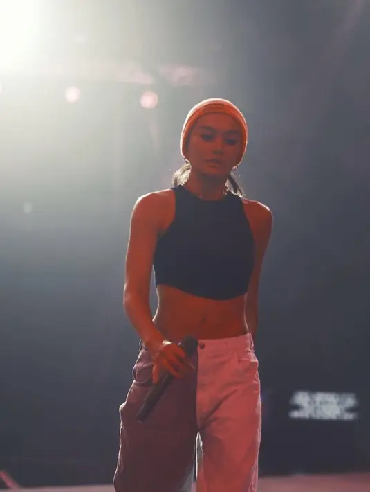 Saat konser, Agnez Mo mengenakan strappy top hitam dari Breshka seharga Rp139 ribuan, dipadukan dengan two tone mom trousers dari Breshka seharga Rp599 ribuan. @agnezmo.