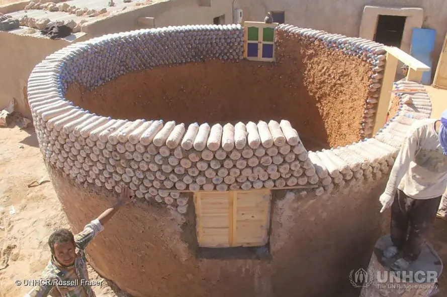 Membangun rumah memang pekerjaan yang butuh banyak bahan, salah satunya adalah bata. Namun pria ini gunakan botol bekas agar lebih murah. (UNHCR/Russell Fraser)