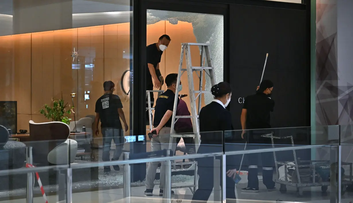 Para staf memperbaiki pintu kaca sebuah toko furnitur di pusat perbelanjaan Siam Paragon. (Lillian SUWANRUMPHA/AFP)