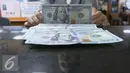 Petugas menunjukkan Dolar AS di toko penukaran uang di Jakarta, Selasa (7/6). Langkah wait and see para pelaku bisnis menambah tekanan terhadap dollar AS. Mata uang dollar AS terhadap rupiah dibuka Rp13.361. (Liputan6.com/Angga Yuniar)