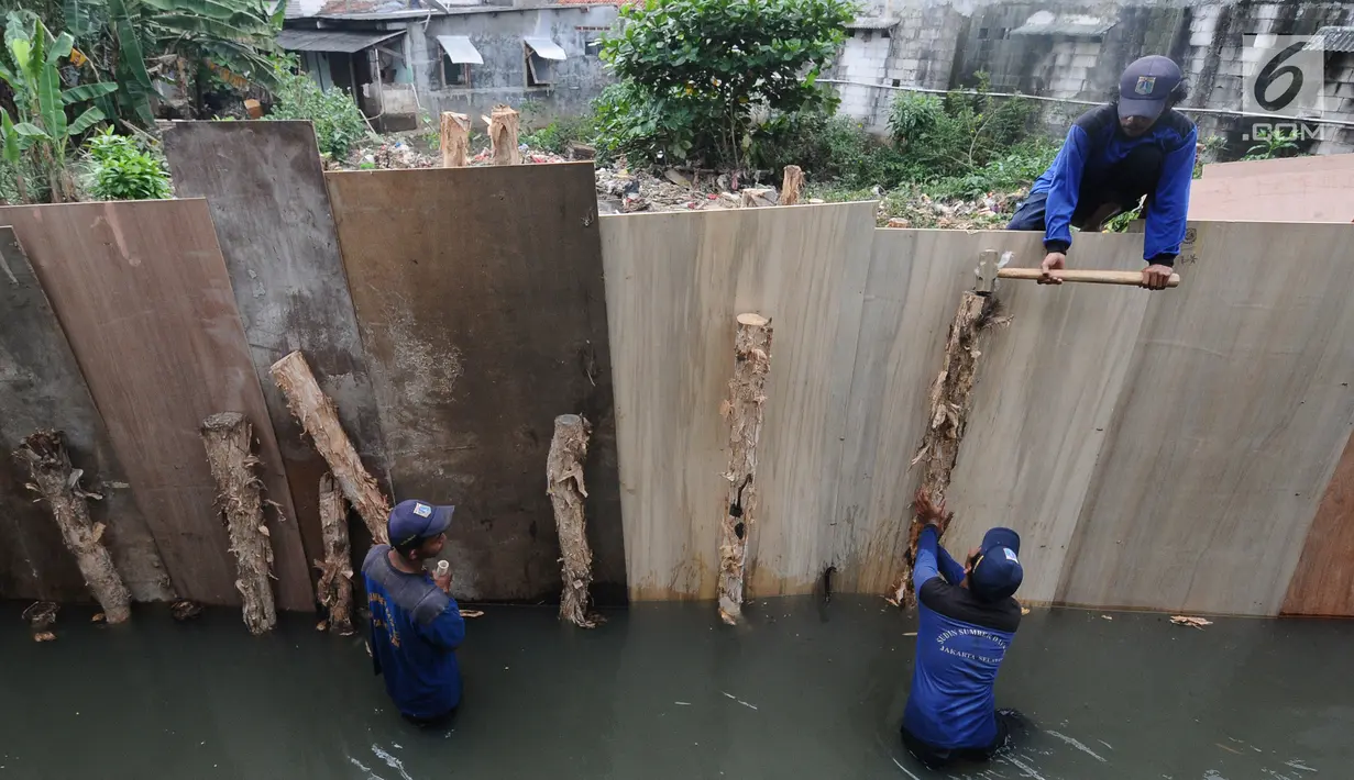 Pekerja Suku Dinas Sumber Daya Air (SDA) memperbaiki tanggul yang kembali jebol di kawasan Jati Padang, Pasar Minggu, Jakarta Selatan, Kamis (18/4). Tanggul jebol akibat derasnya air kali Pulo akibat hujan deras yang melanda kawasan Jakarta pada 16 April 2019 lalu. (Liputan6.com/Herman Zakharia)