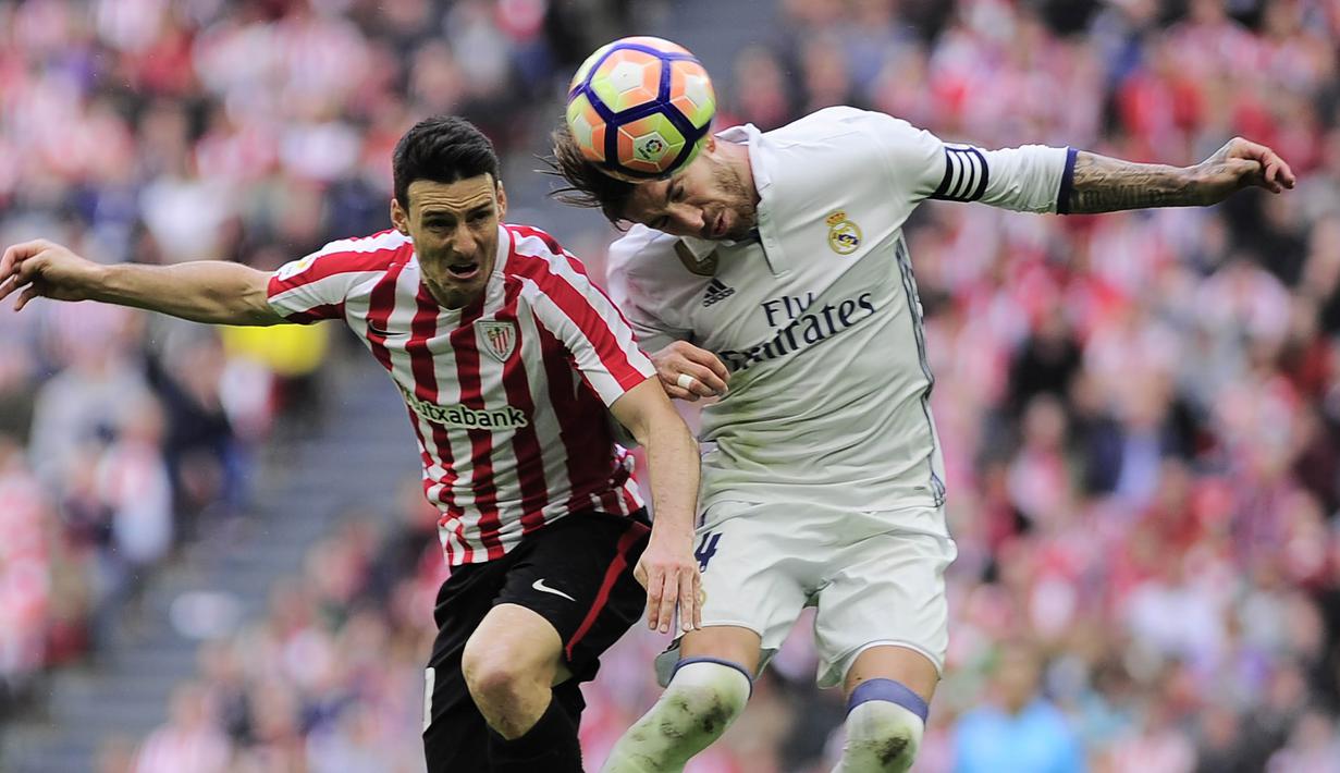 Penyerang Athletic Bilbao, Aritz Aduriz, duel udara dengan bek Real Madrid, Sergio Ramos. Berdasarkan statistik, Madrid mencatatkan 48 persen penguasaan bola berbanding 52 persen milik Bilbao. (AFP/Ander Gillenea)