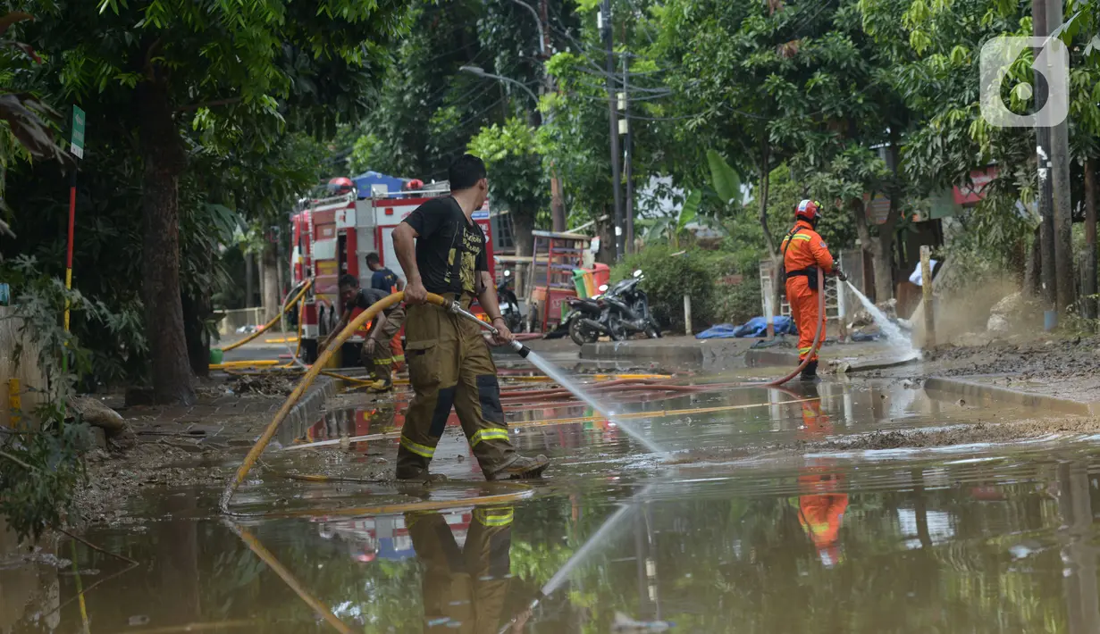 Sejumlah petugas pemadam kebakaran membersihkan sisa lumpur pascabanjir yang merendam kawasan Bukit Duri, Jakarta, Sabtu (4/1/2020). Meski banjir sudah mulai surut, jalan-jalan dan permukiman warga masih tertutup lumpur tebal. (merdeka.com/Imam Buhori)