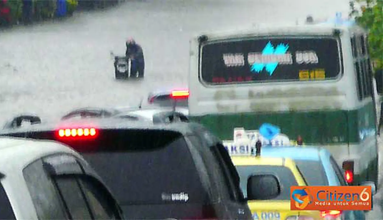 Seorang pengendara motor terjebak di tengah genangan banjir.