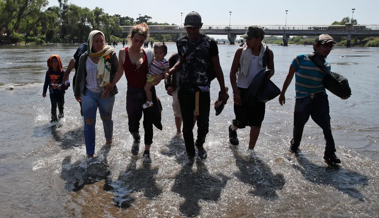 Migran Amerika Tengah menyeberangi Sungai Suchiate dengan berjalan kaki dari Guatemala ke Meksiko, Ciudad Hidalgo, Meksiko, Senin (20/1/2020). Lebih dari seribu migran Amerika Tengah yang terdampar di Guatemala berjalan massal untuk menuju Amerika Serikat. (AP Photo/Moises Castillo)