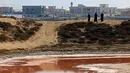 Sejumlah orang mengamati danau merah muda di Ras Al Khaimah di Uni Emirat Arab (UEA) pada 26 Januari 2021. Foto-foto danau merah muda itumenjadi viral di media sosial setelah seorang remaja Emirat menemukannya. (GIUSEPPE CACACE/AFP)