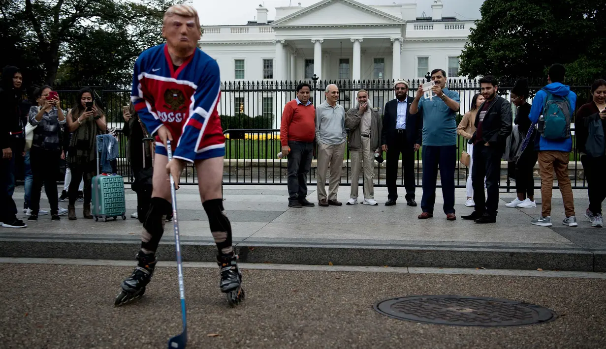 Wisatawan melihat seorang pria mengenakan topeng Presiden AS Donald Trump dan kostum tim hoki Rusia saat unjuk rasa di luar Gedung Putih di Pennsylvania Avenue di Washington, DC, (29/10). (AFP Photo/Brendan Smialowski)