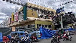 Pengendara berjalan melewati gedung yang rusak setelah gempa bumi berkekuatan magnitudo 7,8 di Kota General Santos, Filipina, pada Senin 8 Juni 2026. (Edwin Espejo/AFP)