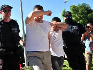Dua dari 8 perwira militer pendukung kudeta di Turki dikawal polisi Yunani di kota Alexandroupoli, Minggu (17/7). 8 pria yang terbang dengan helikopter militer Turki itu ditahan petugas keamanan Yunani karena masuk secara ilegal. (Sakis MITROLIDIS/AFP)