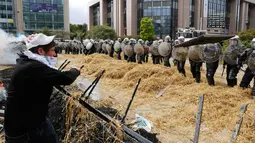Sejumlah polisi berjaga saat peternak dan petani melempari jerami ditengah aksi protes pada pertemuan Menteri-menteri Eropoa di Brussels, Belgia, 7 September 2015. Aksi tersebut menuntut bantuan harga murah dan biaya yang tinggi. REUTERS/Yves Herman)