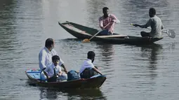 Seorang pria dan seorang anak laki-laki mendayung perahu selama jam sekolah di Danau Dal di Srinagar, India, Rabu (11/5/2022). Danau terbesar di negara bagian tersebut penting untuk kegiatan perikanan, perairan, rekreasi, dan pariwisata. (TAUSEEF MUSTAFA / AFP)