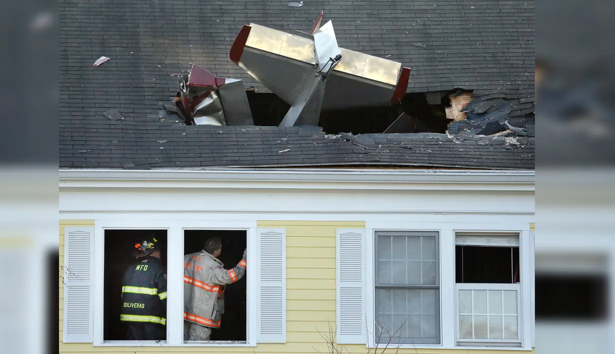 Petugas memeriksa lokasi jatuhnya pesawat ringan bermesin satu yang menabrak atap kondominium di Methuen, Massachusetts, (1/3). Pesawat ini terbang dari Bandara Lawrence Municipal menyeberangi Sungai Merrimack. (AP/Elise Amendola)