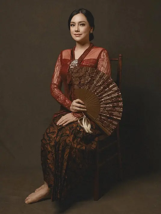Celine Evangelista tampil mengenakan kebaya merah brokat semi transparan. Ia memadukannya dengan bawahan kain batik coklat dan bros keemasan. [@celine_evangelista]