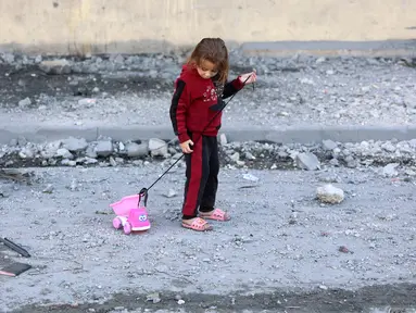 Seorang anak perempuan Palestina menarik mainannya di jalan yang dipenuhi puing-puing di Jabalia, Jalur Gaza utara pada 20 November 2024. (Omar AL-QATTAA/AFP)