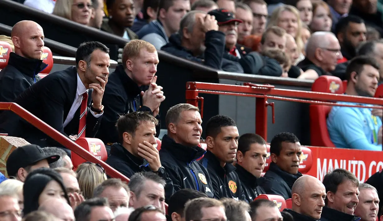 Pelatih sementara Manchester United, Ryan Giggs (berdasi) duduk di samping Paul Scholes menyimak serius permainan timnya saat berlaga melawan Norwich City  di Old Trafford, Inggris (27/4/2014). (REUTERS/Nigel Roddis) 