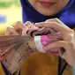 Petugas Bank menghitung uang pecahan Rp100.000 di Bank Bukopin Syariah, Jakarta, Selasa (29/12). Di pasar spot, Senin (28/12), rupiah melemah tipis 0,08% ke Rp 13.642 per dollar AS. (Liputan6.com/Angga Yuniar)