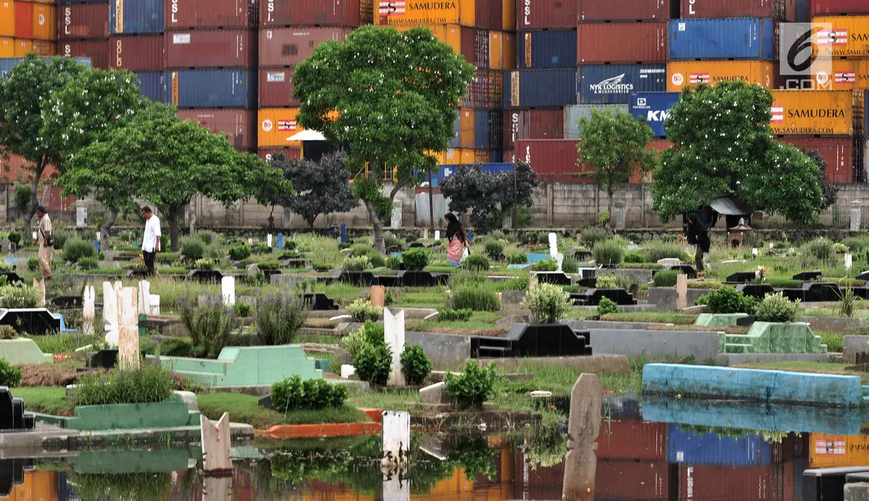 Peziarah melintasi makam yang terendam banjir di Taman Pemakaman Umum (TPU) Semper, Jakarta, Selasa (4/12). (Merdeka.com/Iqbal S. Nugroho)