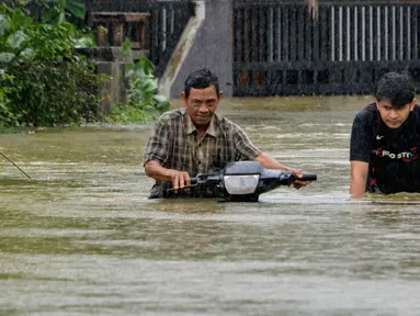 Warga mendorong sepeda motornya menerebos banjir setelah tiga hari diguyur hujan lebat di Banda Aceh, Aceh, Sabtu (9/5/2020). Banjir akibat intensitas hujan tinggi tersebut mengakibatkan sebagian besar kawasan di ibu kota Provinsi Aceh ini digenangi air. (Photo by CHAIDEER MAHYUDDIN/AFP)