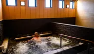 Seorang pria bersantai dalam kolam renang indoor di pemandian air panas Jepang atau onsen di Yokohama, prefektur Kanagawa pada 29 Mei 2020. Dengan pencabutan status darurat nasional pada Senin (25/5) lalu, banyak bisnis yang mulai beroperasi kembali tak terkecuali dengan onsen. (Behrouz MEHRI/AFP)